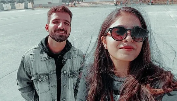 Два человека на городской улице улыбаются и смотрят друг на друга повседневная одежда архитектура зданий дневной свет уличная сцена дружелюбная атмосфера